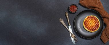 Tabakta ızgara Halloumi peyniri. Çatal bıçak takımı, piknik ya da barbekü için geleneksel yemek. Modaya uygun sert ışık, koyu gölge, düz zemin, siyah taş beton zemin, afiş biçimi