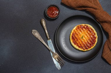 Tabakta ızgara Halloumi peyniri. Çatal bıçak takımı, piknik ya da barbekü için geleneksel yemek. Modaya uygun sert ışık, koyu gölge, düz zemin, siyah taş beton zemin, üst manzara