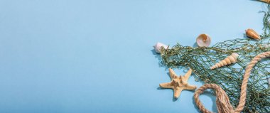 Deniz kabukları, deniz yıldızları ve balıkçı ağıyla donatılmış mavi bir arka plan. Çeşitli deniz hayvanları, tatil konsepti. Modaya uygun sert ışık, koyu gölge, düz döşeme, afiş biçimi