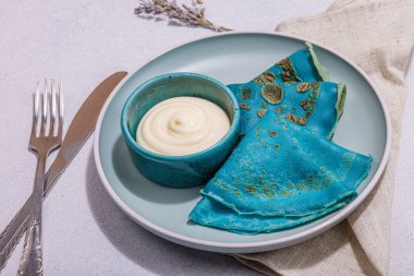 Krema soslu ince mavi krep. Sağlıklı vegan, laktoz ve glütensiz yemek, kahvaltı konsepti. Modaya uygun sert ışık, karanlık gölge, aydınlık taş beton zemin, kapat