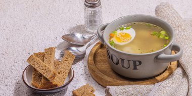 Haşlanmış yumurtalı köfte çorbası, ditalini makarna, sebze ve taze otlar. Sağlıklı tavuk çorbası, akşam yemeği için geleneksel sıcak yemek. Sert ışık, koyu gölge, taş beton zemin, afiş biçimi