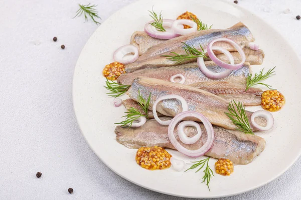 stock image Salted herring with dijon mustard, dill and red onion rings. Marinated filleted fish on light stone concrete background, flat lay, close up