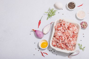 Çiğ et, baharat ve otlar. Pirzola ya da köfte pişirmek için geleneksel malzemeler. Modaya uygun sert ışık, karanlık gölge, aydınlık taş arkaplan, üst görünüm