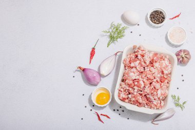 Çiğ et, baharat ve otlar. Pirzola ya da köfte pişirmek için geleneksel malzemeler. Modaya uygun sert ışık, karanlık gölge, aydınlık taş arkaplan, üst görünüm