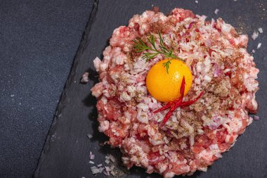 Ev yapımı kıyma, baharat ve otlar. Pirzola ya da köfte pişirmek için geleneksel ham malzemeler. Modaya uygun sert ışık, karanlık gölge, aydınlık taş arkaplan, üst görünüm