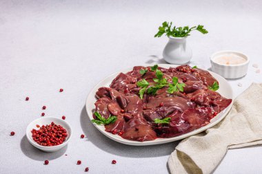 Taş zeminde çiğ tavuk ciğeri. Yemek, maydanoz ve kırmızı biber için taze malzemeler hazır. Modaya uygun sert ışık, koyu gölge, düz alan, kopyalama alanı