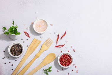 Ahşap mutfak aletleri, baharatlar ve bitkilerle mutfak arka planı. Sağlıklı yiyecekler için hazır, düz konum. Sert ışık, karanlık gölge, aydınlık taş zemin, üst manzara