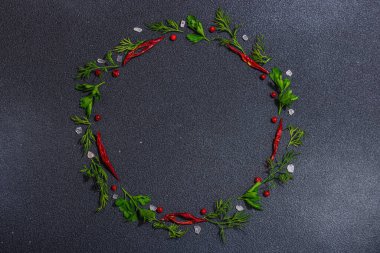 Taze maydanoz ve dereotlu çelenk, acı biber, koyu beton zeminde deniz tuzu. Yuvarlak çerçeve, modern sert ışık, koyu gölge, düz yer, üst manzara