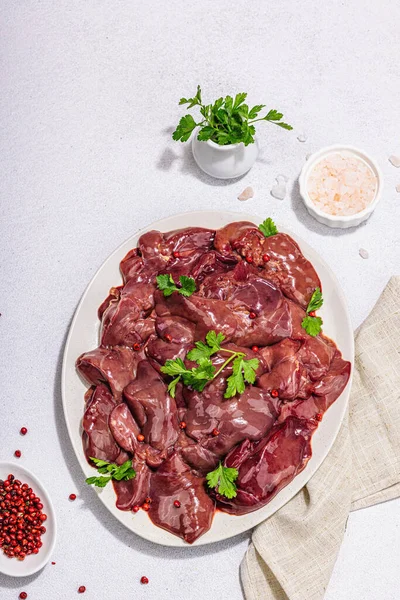 stock image Raw chicken liver on stone background. Fresh ingredients ready for cooking, parsley, red pepper. Trendy hard light, dark shadow, flat lay, top view