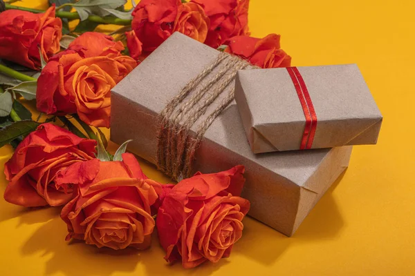 stock image Zero waste gift concept. Bright roses, wrapped in craft paper surprise box for Anniversary, Mothers or Valentines Day. Happy birthday greeting card, orange background, close up