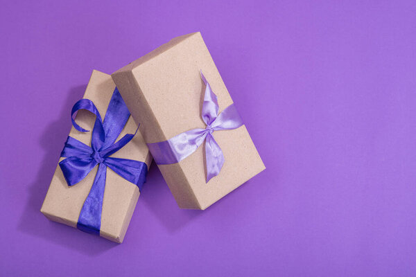 Zero waste gift concept. Wrapped in craft paper surprise box for Anniversary, Mothers or Valentines Day. Happy birthday greeting card, purple background, flat lay, top view