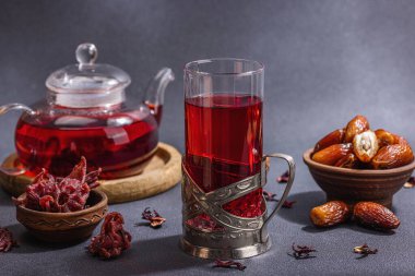 Hibiscus sıcak çay ve hurma. Koyu beton zeminde iftar ya da Suhoor yemeği için geleneksel Ramazan Kareem konsepti. Arap tatlısı, sert ışık, karanlık gölge, kopyalama alanı.