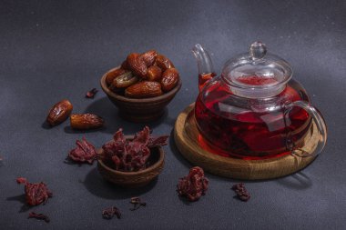 Hibiscus sıcak çay ve hurma. Koyu beton zeminde iftar ya da Suhoor yemeği için geleneksel Ramazan Kareem konsepti. Arap tatlısı, sert ışık, karanlık gölge, kopyalama alanı.
