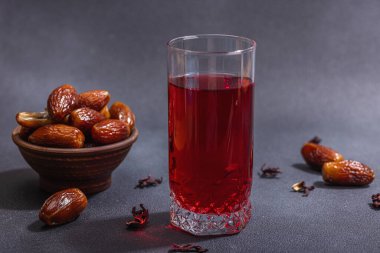 Hibiscus sıcak çay ve hurma. Koyu beton zeminde iftar ya da Suhoor yemeği için geleneksel Ramazan Kareem konsepti. Arap tatlısı, sert ışık, karanlık gölge, kopyalama alanı.
