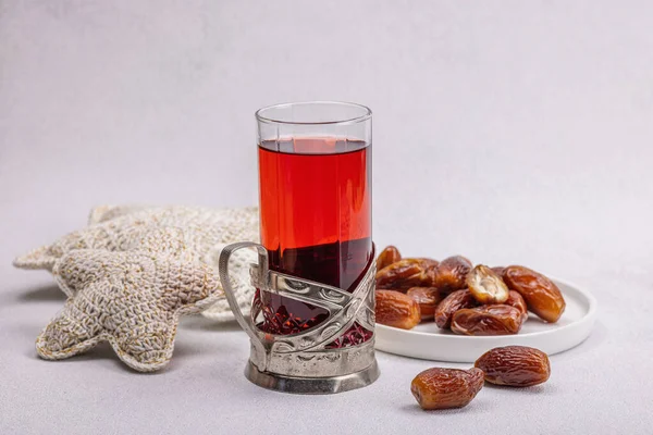 Hibiscus sıcak çay ve hurma. Hafif beton zeminde iftar ya da Suhoor yemeği için geleneksel Ramazan Kareem konsepti. Arap tatlısı, sert ışık, karanlık gölge, kopyalama alanı.