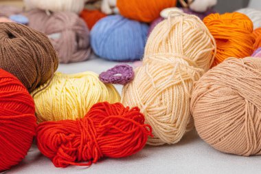 Örgü ve özel el işi aletleri için renkli bir demet iplik. El yapımı, hobi, tığ işi konsepti. Aydınlık taş arka planda aksesuarlar ve eşyalar, kapatın.