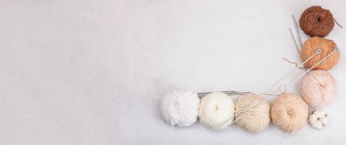 Pastel doğal renklerde örgü ve özel el işi aletleri için iplik dizileri. El yapımı, hobi, tığ işi konsepti. Işık taşı arkaplanı, afiş biçimi ve malzemeler