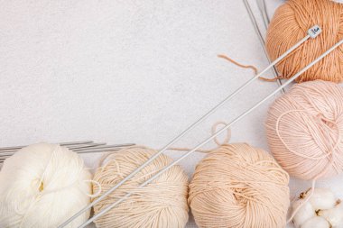 Pastel doğal renklerde örgü ve özel el işi aletleri için iplik dizileri. El yapımı, hobi, tığ işi konsepti. Işık taşı, beton zemin, üst görünüm...