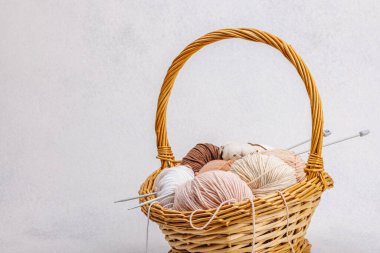 Sepette örgü örmek için bir demet pastel iplik. El yapımı, hobi, tığ işi konsepti. Işık taşı arkaplanındaki dekorlar ve özel sanatlar araçları, boşluğu kopyala