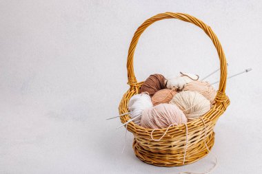 Sepette örgü örmek için bir demet pastel iplik. El yapımı, hobi, tığ işi konsepti. Işık taşı arkaplanındaki dekorlar ve özel sanatlar araçları, boşluğu kopyala