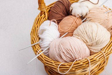 Sepette örgü örmek için bir demet pastel iplik. El yapımı, hobi, tığ işi konsepti. Işık taşı arkaplanındaki dekorlar ve özel sanatlar araçları, kapatın