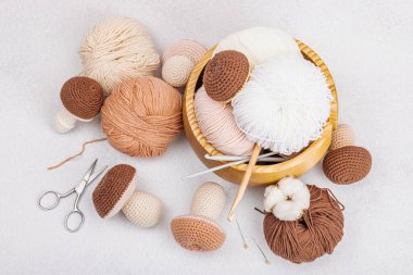 Örgü örmek için bir demet iplik. Tığ işi mantar, el yapımı, hobi konsepti. Işık taşı arkaplan, üst görünüm üzerine dekorlar ve özel sanatlar araçları