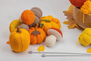 Örgü örmek için bir demet iplik. Tığ işi mantarlar, balkabakları, el yapımı, sonbahar hobisi. Işık taşı arkaplanındaki dekorlar ve özel sanatlar araçları, boşluğu kopyala