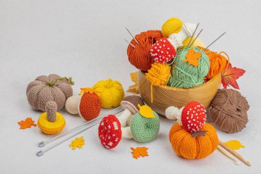 Örgü örmek için bir demet iplik. Tığ işi mantarlar, balkabakları, el yapımı, sonbahar hobisi. Işık taşı arkaplanındaki dekorlar ve özel sanatlar araçları, boşluğu kopyala