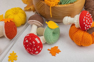 Örgü örmek için bir demet iplik. Tığ işi mantarlar, balkabakları, el yapımı, sonbahar hobisi. Işık taşı arkaplanındaki dekorlar ve özel sanatlar araçları, kapatın