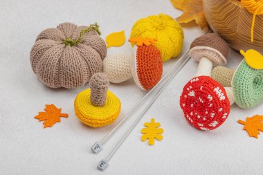 Örgü örmek için bir demet iplik. Tığ işi mantarlar, balkabakları, el yapımı, sonbahar hobisi. Işık taşı arkaplanındaki dekorlar ve özel sanatlar araçları, kapatın