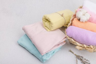 Giysilerin dikey depolanması. Bahar dolabı temizliği, çevre dostu hasır sepet. Pastel renkli bebek tişörtleri, makine yıkadıktan sonra katlanmış. Hafif taş arkaplan, boşluğu kopyala
