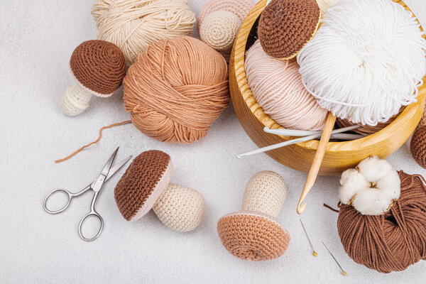 Set of clew of thread for knitting. Crocheted mushrooms, handmade, hobby concept. Props and special craft tools on light stone concrete background, top view