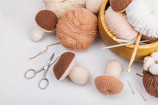 Set of clew of thread for knitting. Crocheted mushrooms, handmade, hobby concept. Props and special craft tools on light stone concrete background, top view