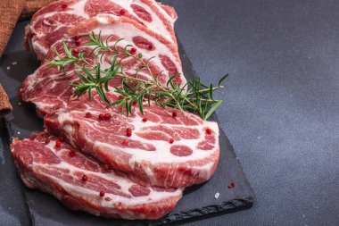 Çiğ domuz eti. Biftek, kırmızı biber, sarımsaklı karanfil, deniz tuzu ve taze biberiye. Moda standı, siyah arkaplan, düz yatış, kopyalama alanı