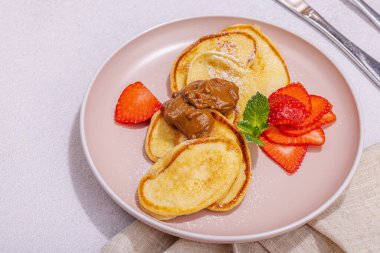 Süzme peynirli krep, şurup, çilekli krep, pembe tabakta nane ve pudra şekeri. Seçici odaklanma, lezzetli kahvaltı. Moda taşı beton arkaplan, kopyalama alanı