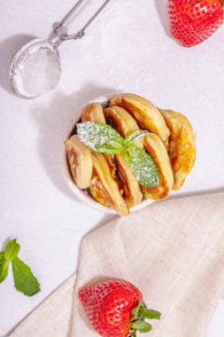 Süzme peynirli krep, şurup, çilekli krep, naneli şeker ve portakal kasesinde pudra şekeri. Seçici odaklanma, lezzetli kahvaltı. Modaya uygun beton zemin, üst görünüm