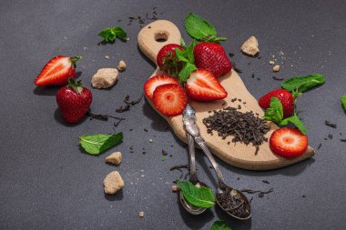 Tazeleyici yaz içeceği. Kuru çay yaprakları, taze meyve ve bitkiler. Çay hazırlamak için gerekli malzemeler, koyu ışık, koyu gölge. Koyu taş zemin, düz zemin, kopyalama alanı