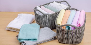 Sepetlerde dikey giysi deposu var. Bahar tuvaleti temizliği, çevre dostu tarzı. Pastel renkli bebek tişörtleri, makine yıkadıktan sonra katlanmış. Hafif ahşap masa, afiş biçimi