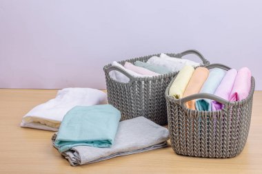 Sepetlerde dikey giysi deposu var. Bahar tuvaleti temizliği, çevre dostu tarzı. Pastel renkli bebek tişörtleri, makine yıkadıktan sonra katlanmış. Hafif ahşap masa, boşluğu kopyala