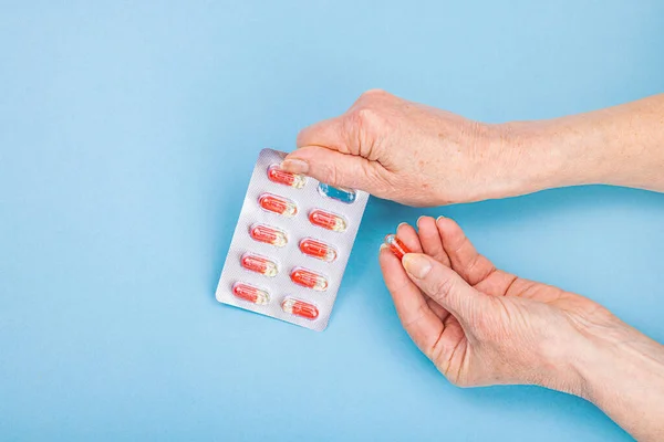 stock image A woman takes medicine. Female hands hold capsules or pills. Treatment, taking vitamins, healthcare concept. Blue background, flat lay, top view