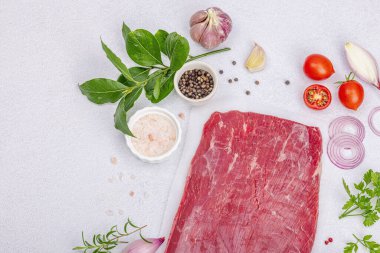 Geleneksel baharat ve otlarla kurutulmuş Bavette bifteği. Taze çiğ et, hafif taş beton arka plan, düz yer, üst manzara.