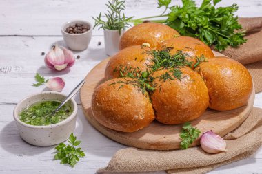 Aromatik sarımsaklı çörekler. Taze pişmiş yiyecekler, geleneksel glütensiz çorba atıştırmalıkları. Maydanoz, baharat, zeytinyağı. Sert ışık, karanlık gölge, beyaz ahşap zemin, kapat