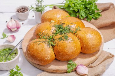 Aromatik sarımsaklı çörekler. Taze pişmiş yiyecekler, geleneksel glütensiz çorba atıştırmalıkları. Maydanoz, baharat, zeytinyağı. Sert ışık, karanlık gölge, beyaz ahşap zemin, kapat