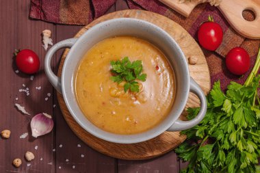 Kokulu sarımsaklı çörekle nohut-domates kremalı çorba. Rahatlatıcı yemekler, nostaljik ruh hali konsepti, sağlıklı vejetaryen yemeği. Ahşap zemin, düz yatış, üst manzara