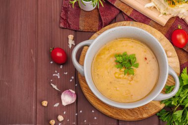 Kokulu sarımsaklı çörekle nohut-domates kremalı çorba. Rahatlatıcı yemekler, nostaljik ruh hali konsepti, sağlıklı vejetaryen yemeği. Ahşap zemin, düz yatış, üst manzara