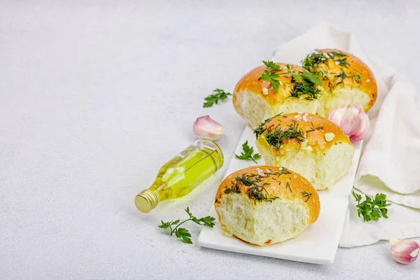 stock image Aromatic garlic buns. Fresh baked goods, a traditional gluten-free soup snack. Parsley, spices, olive oil. Light stone concrete background, copy space