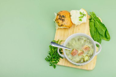 Geleneksel Portekiz çorbası Caldo Verde ve taze fırın. Aromatik sebzeler, servis edilen yemekler, sağlıklı beslenmeye hazır. Modern ahşap tezgah, yeşil arka plan, üst manzara