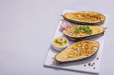 Zeytinyağlı ızgara patlıcan, sarımsak ve yeşillik. Piknik ya da barbekü için geleneksel yiyecekler, vegan sağlıklı yiyecekler. Modern sert ışık, karanlık gölge, taş beton zemin, kopyalama alanı