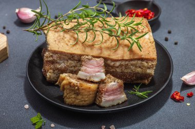 Baharatla pişirilmiş tuzlu, yüksek yağlı et parçaları. Salo, pastırma, domuz yağı, gümüş, tavla. Sarımsak, taze defne yaprağı, biberiye, baharat, biber. Siyah taş beton arka plan, kapat