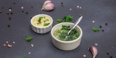 Salata sosu. Krema sosu ve baharatlı sarımsak yağı ve taze yeşillikler. Mutfak arka planı, siyah taş beton, düz döşeme, pankart biçimi